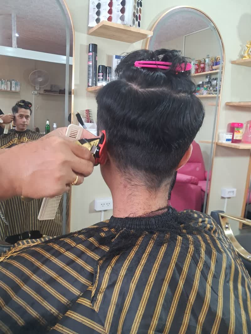 Stylist trimming a client's neckline with clippers and comb