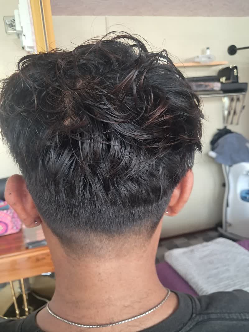 Taper fade with a short neck and tousled dark hair on top