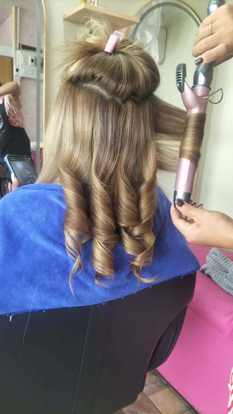 Long blonde hair being curled with a curling iron in the salon