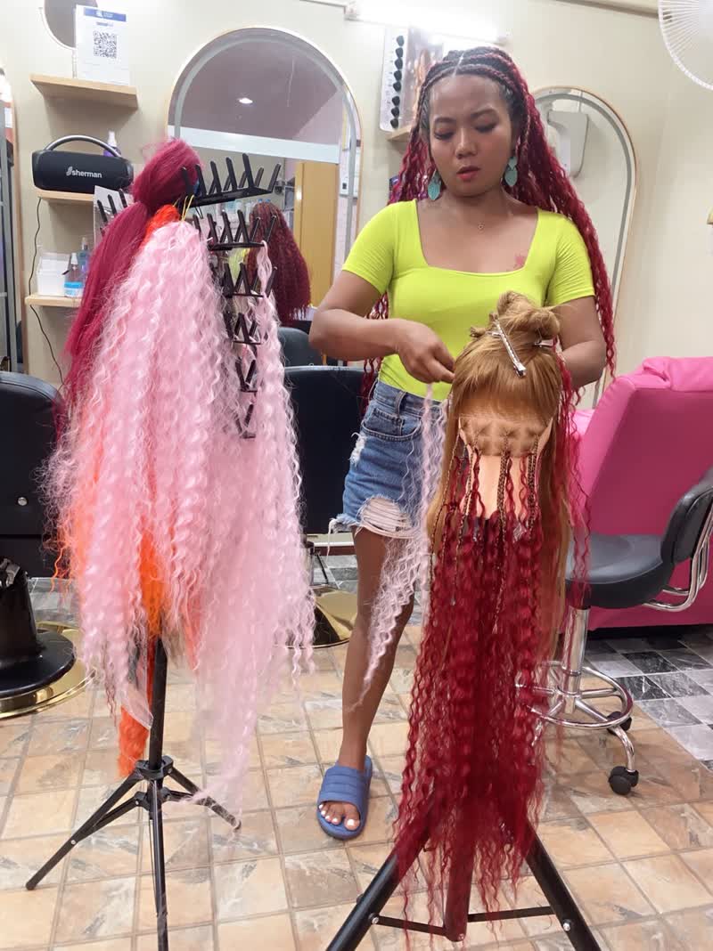 Stylist working on long red braids
