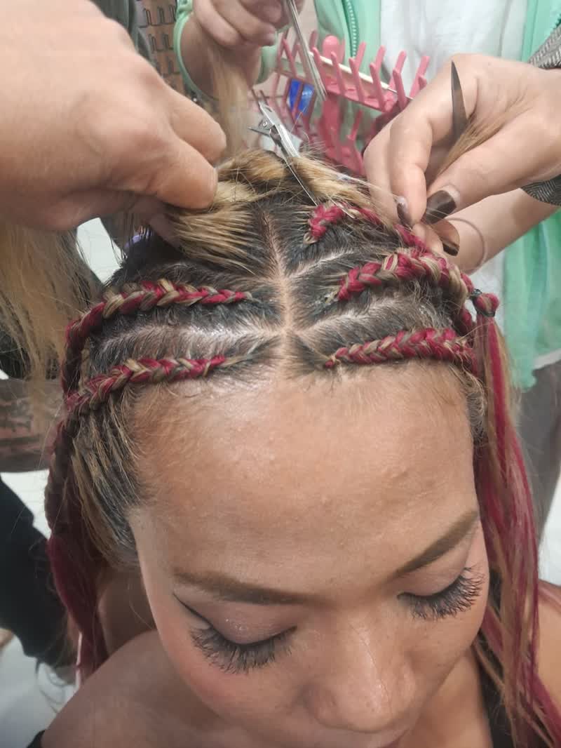 Two stylists sectioning blonde and pink braiding hair